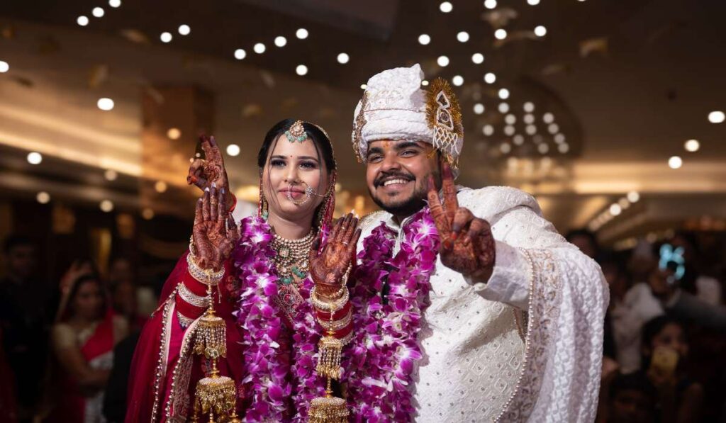 Foreign couple during Indian wedding ceremony wearing traditional attire and exchanging varmala garlands