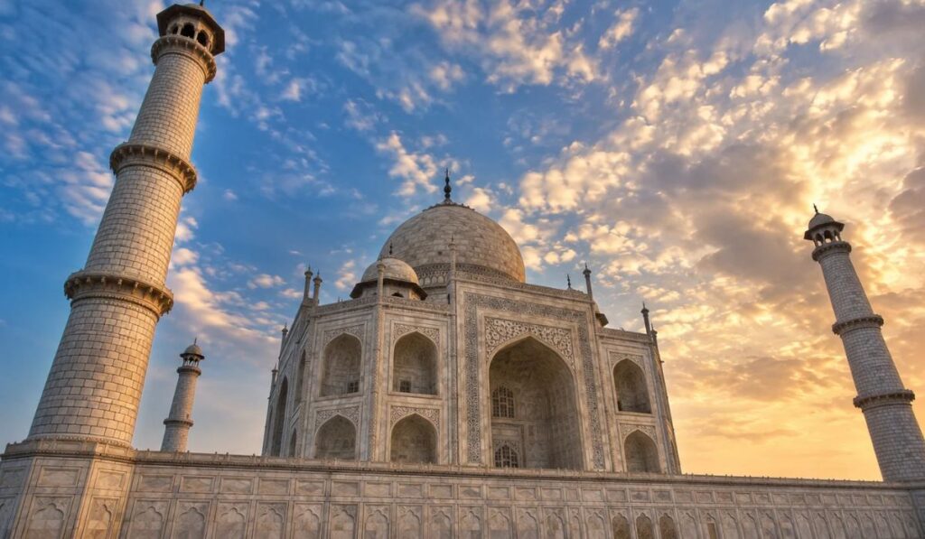 Low-angle Taj Mahal photography perspective emphasizing vertical minaret height against blue sky.