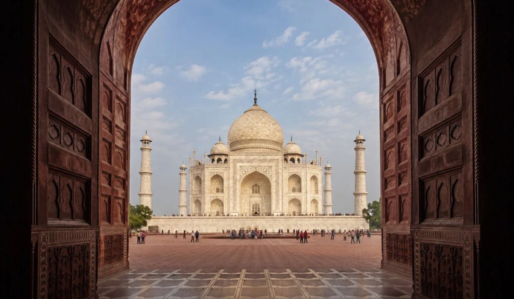 Taj Mahal framed through the dark red sandstone archway of the Great Gate entrance.